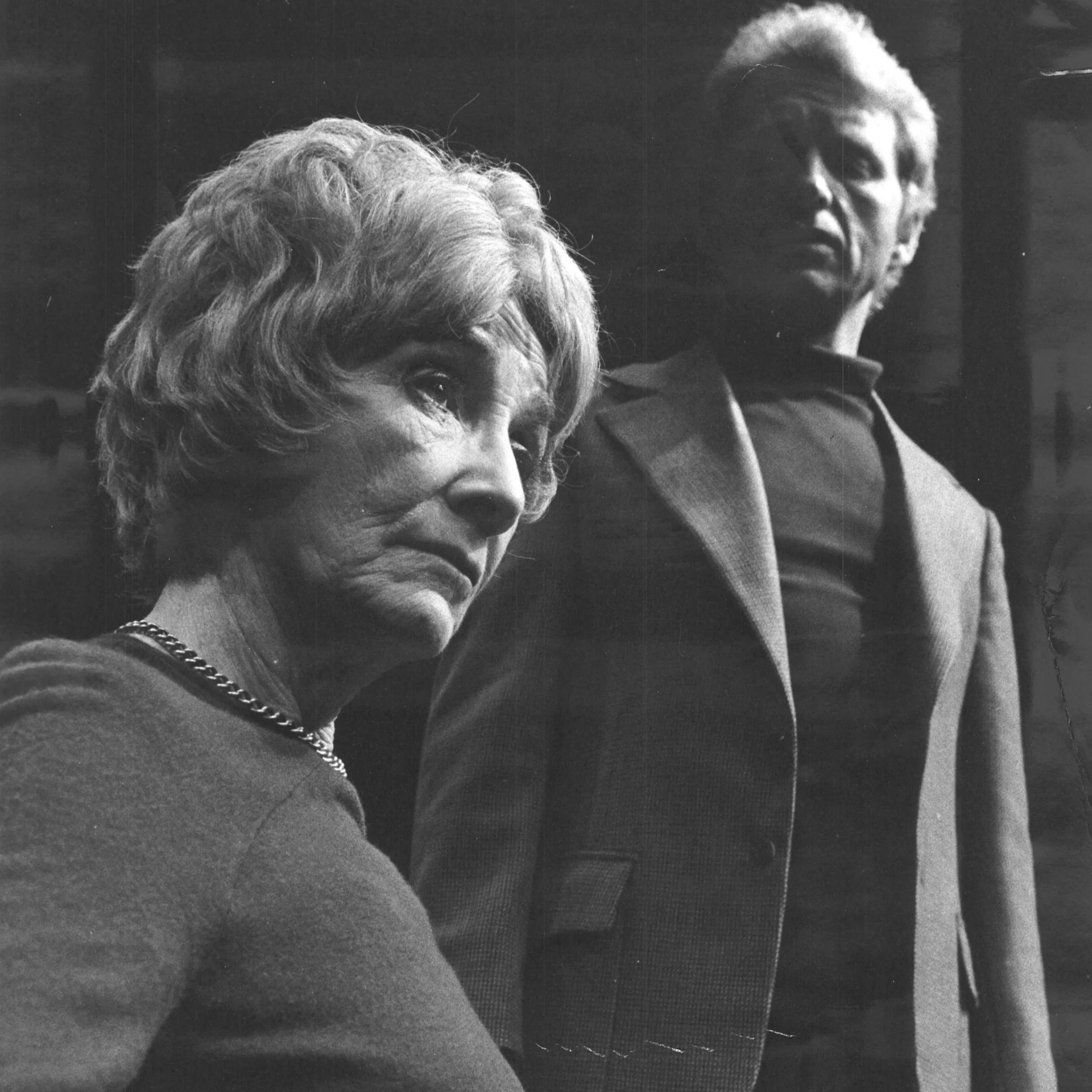 A Man is standing over a woman who is looking away into the distance.