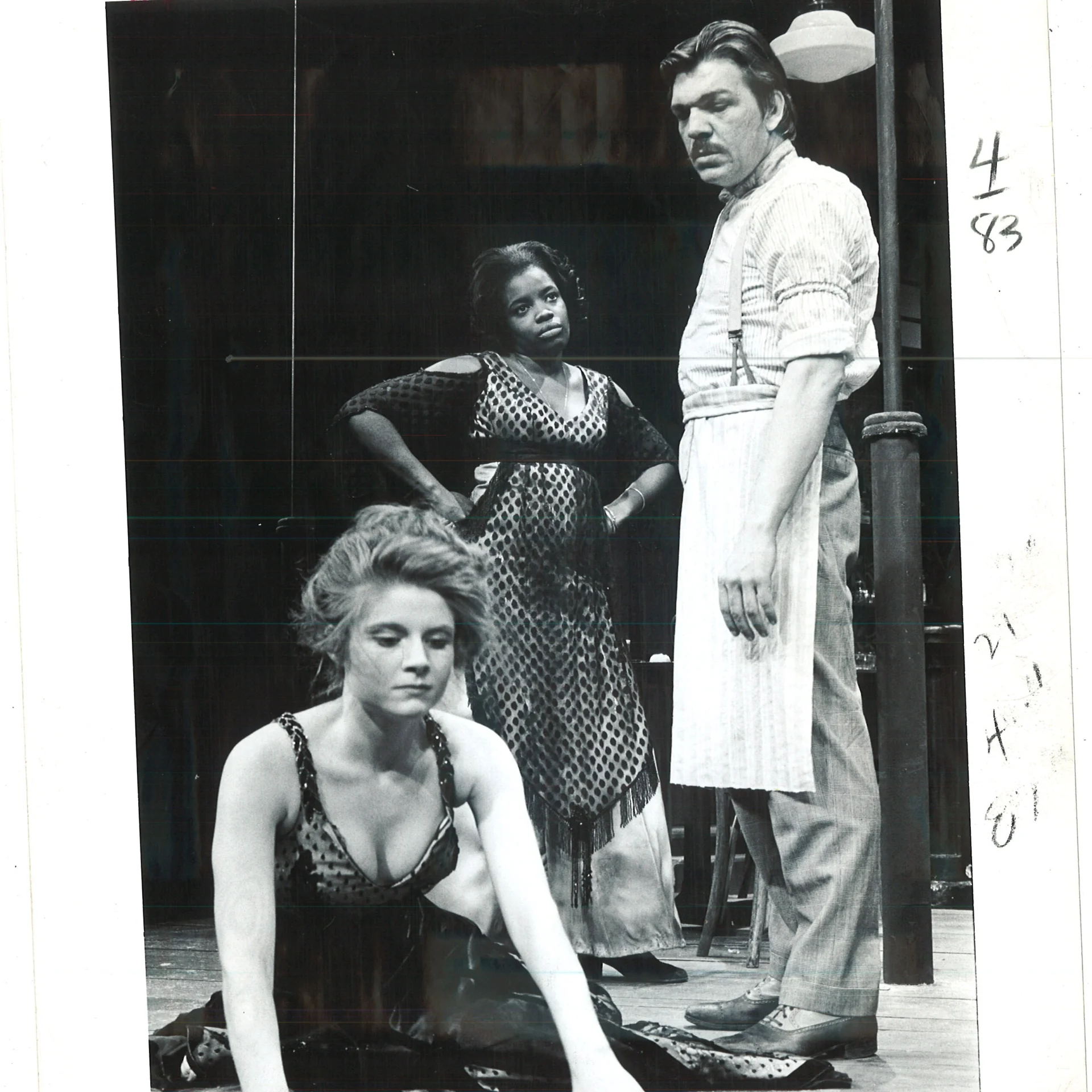 There is a woman on the ground who seems to be looking for something while there's a man and a woman watching behind her.