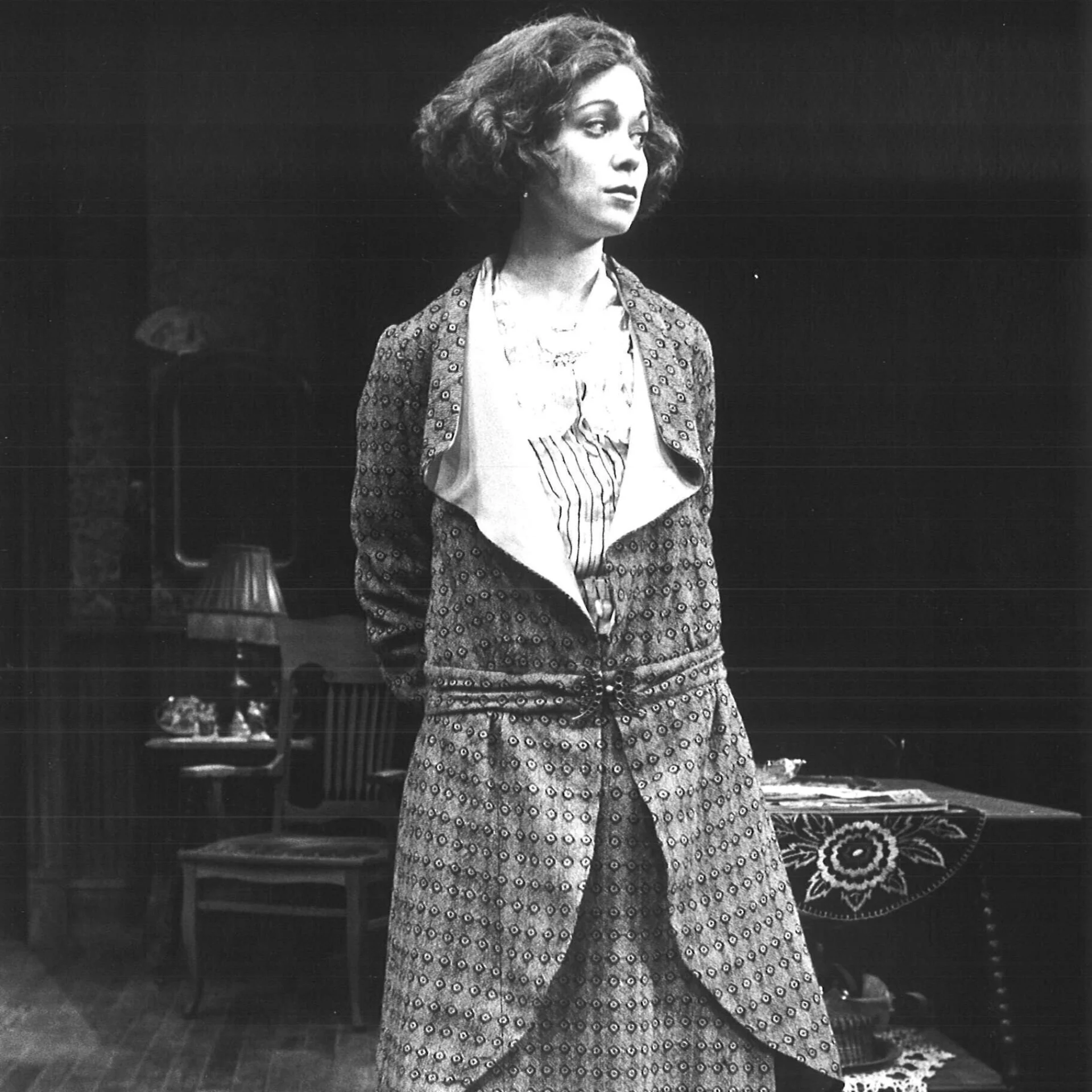 A woman is seen putting her hands behind her back while she looks aways.