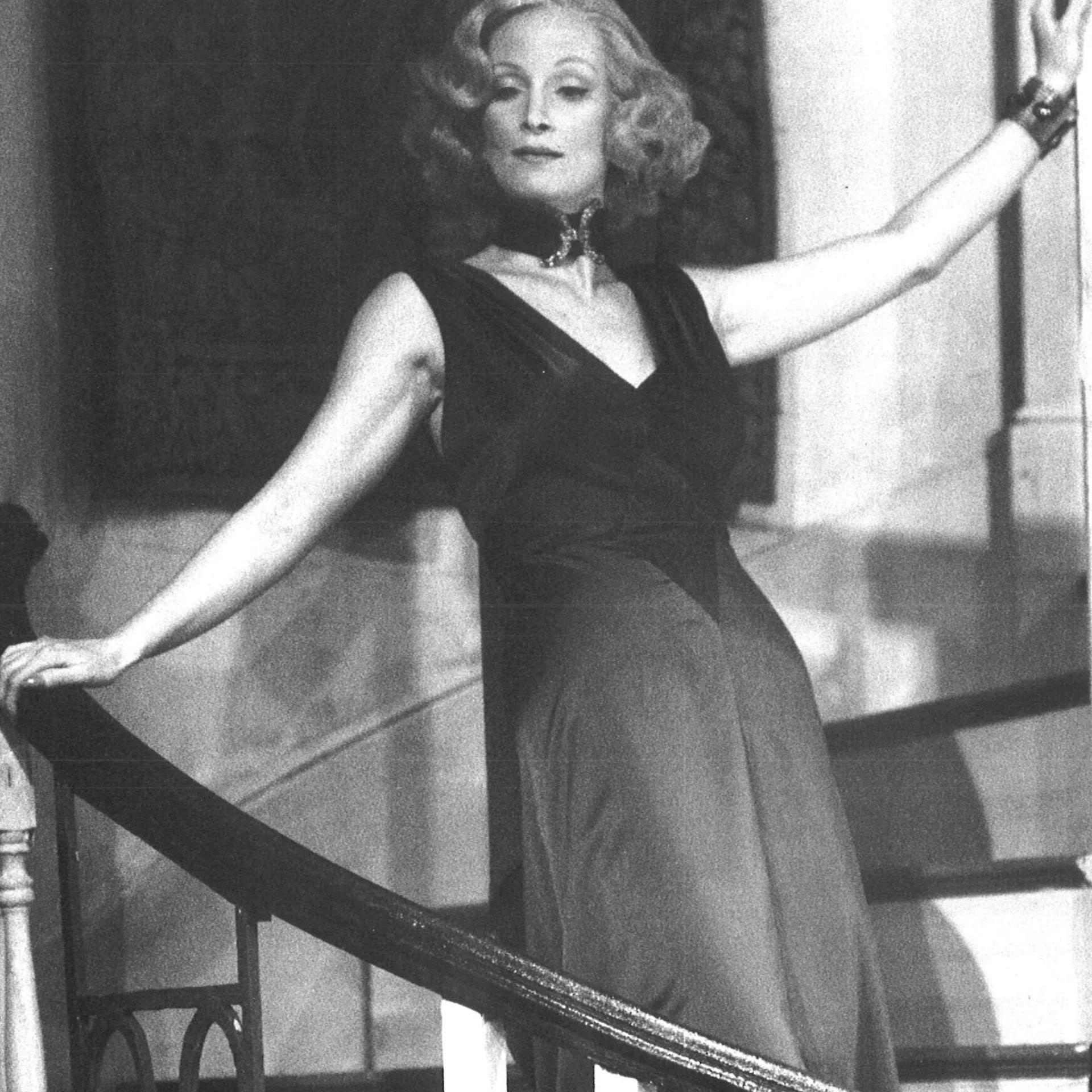A woman is seen posing on a stairway in a black dress.