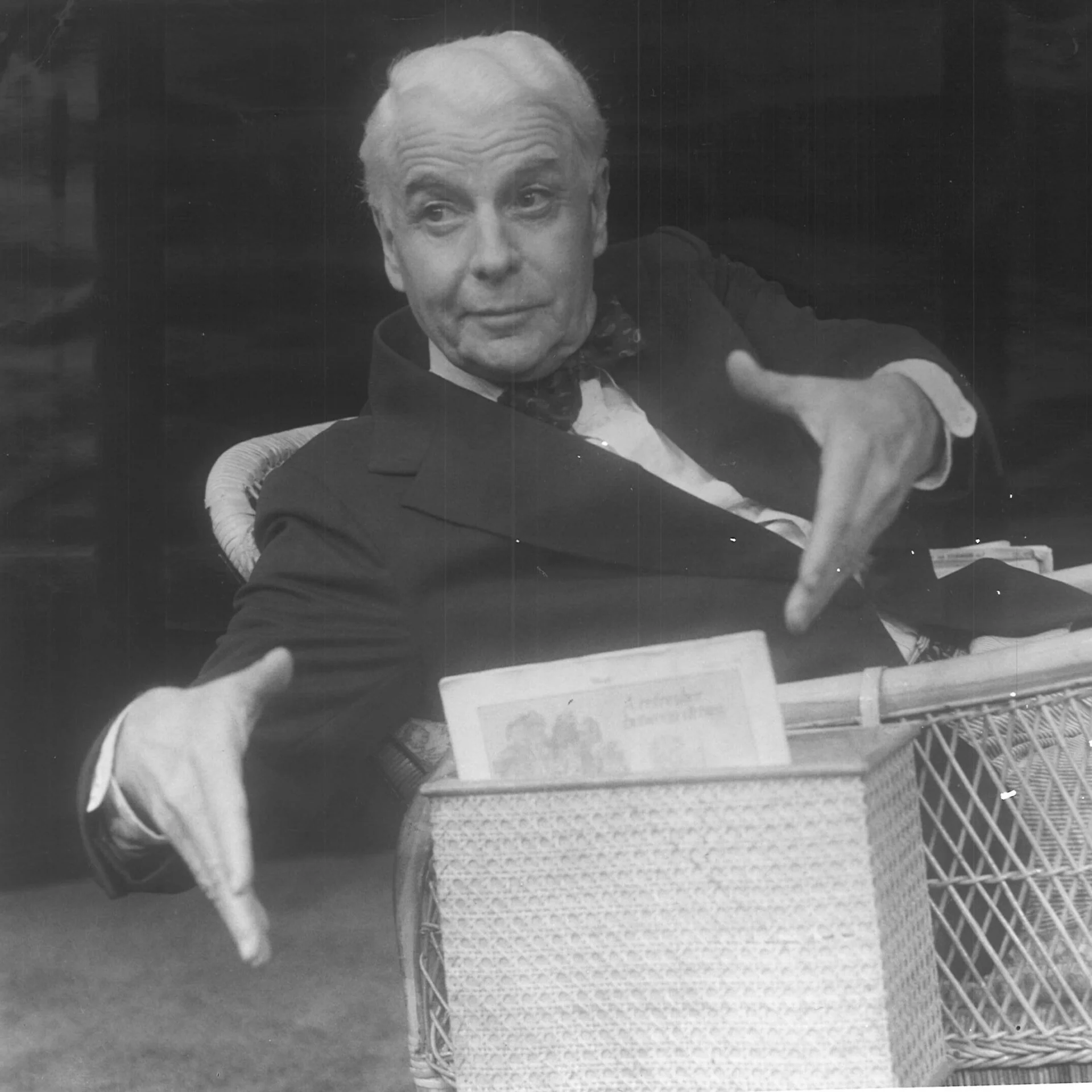 A man is sitting in a chair, extending his hands and looking in the distance