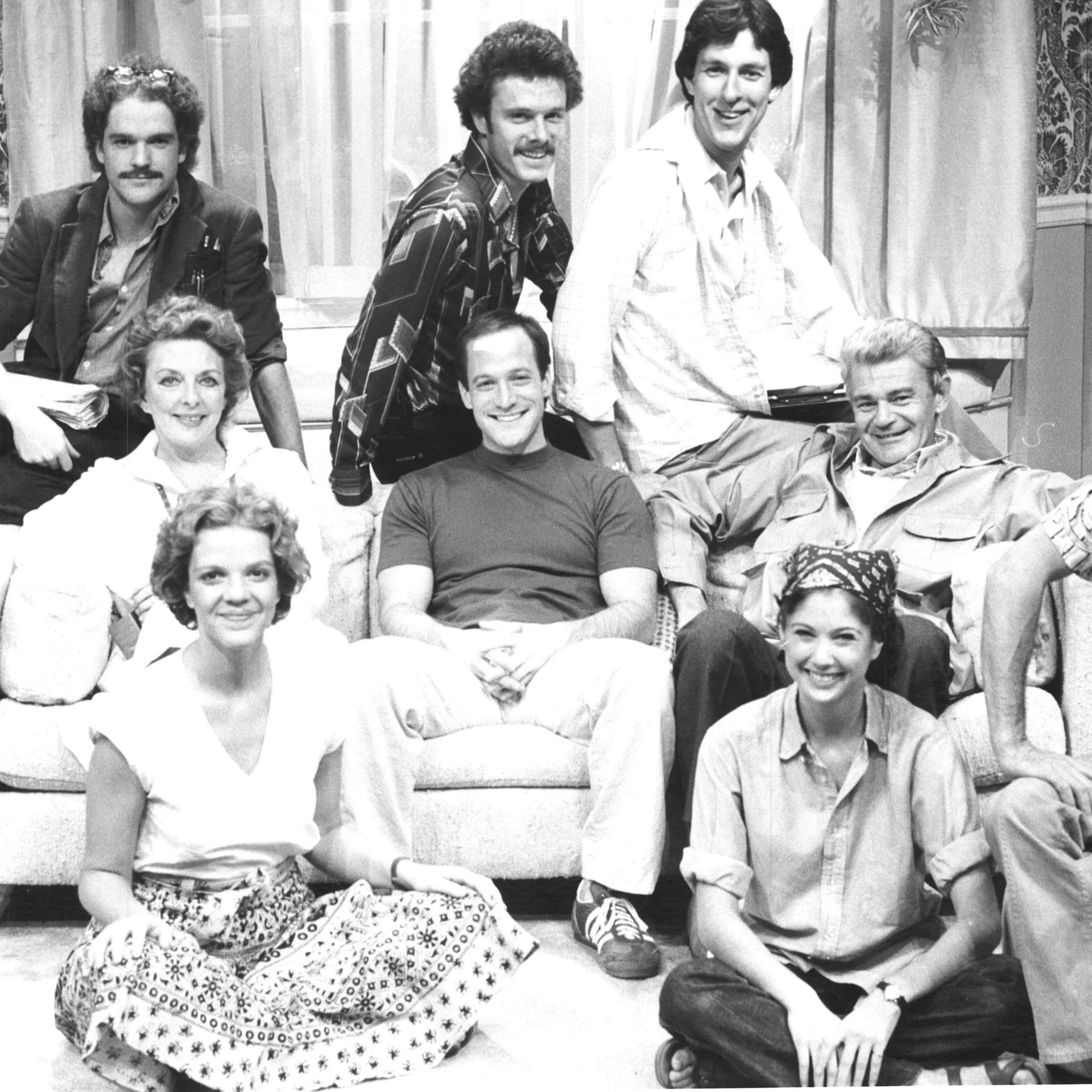 A group of people are seen posing on a couch and around it