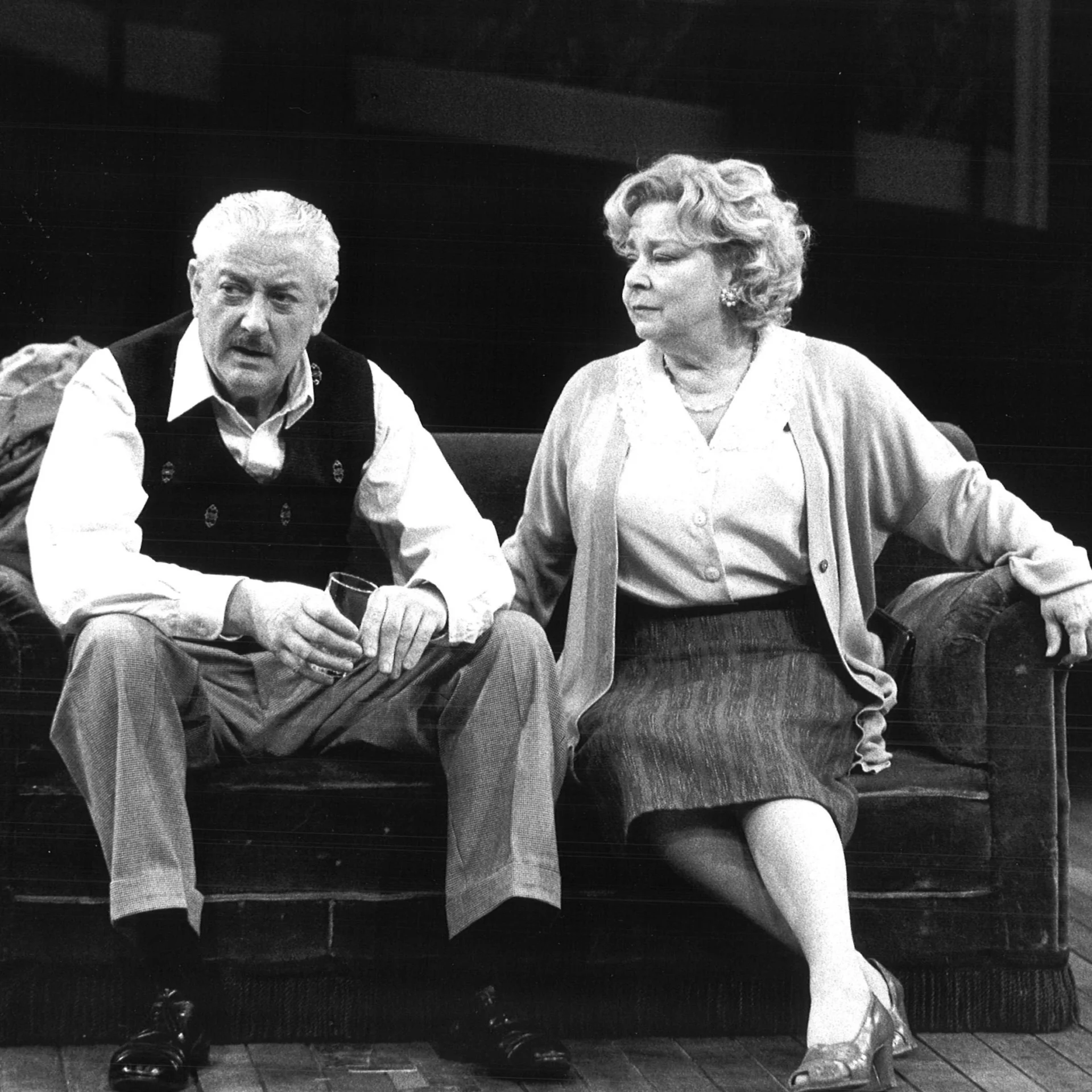 An older man and woman sitting side-by-side on a couch
