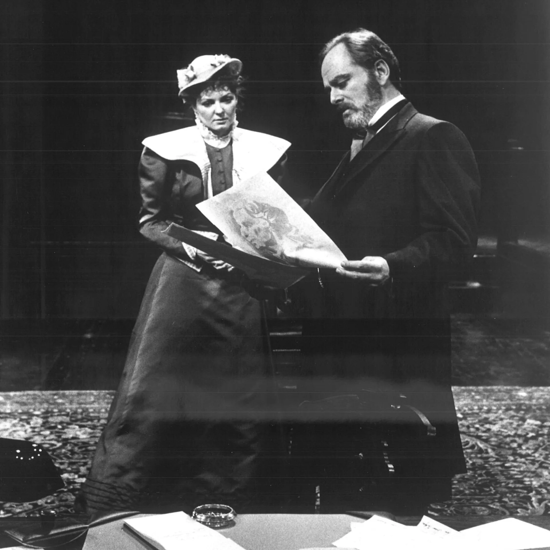 A man and woman are standing together looking at a drawing