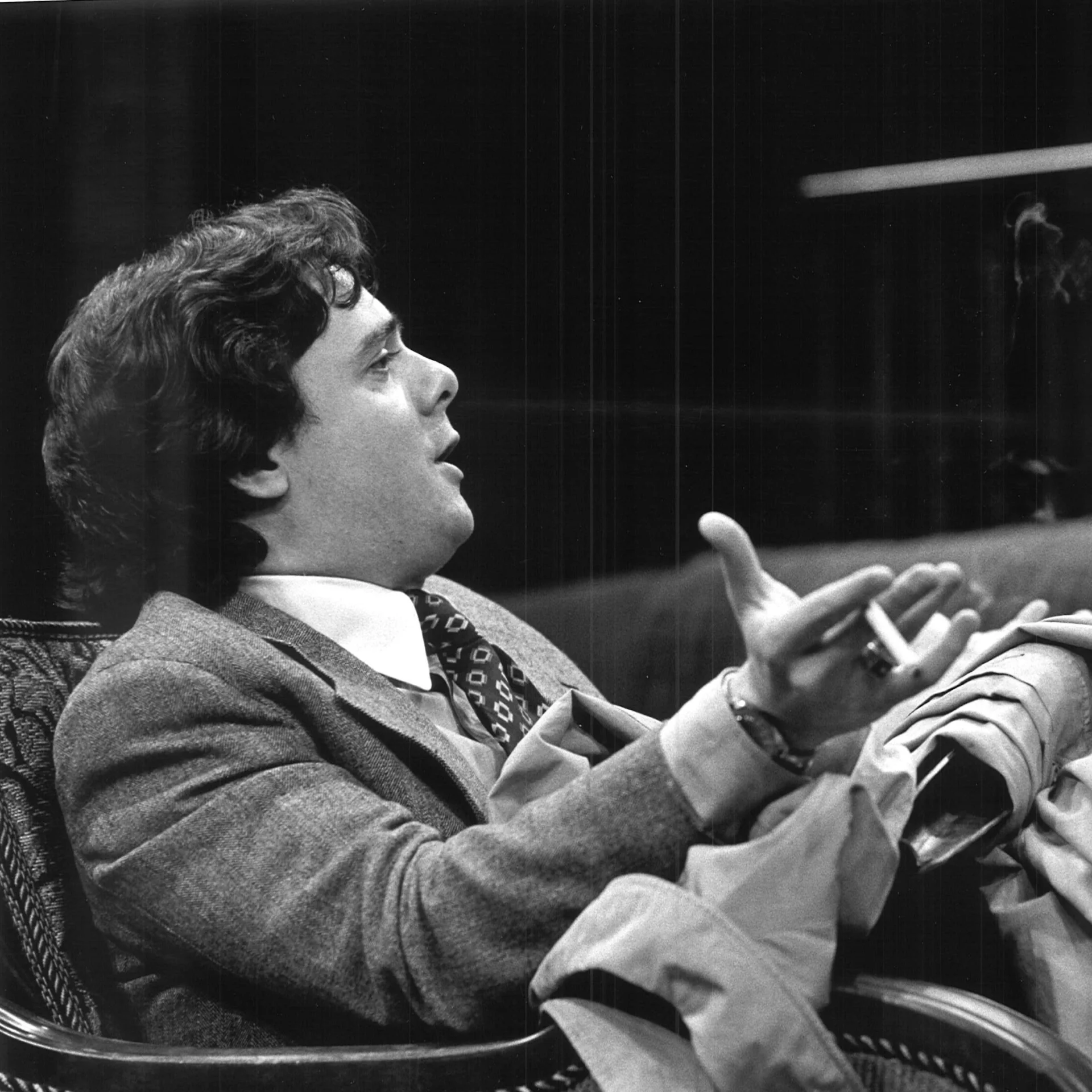 A man is sitting on a chair talking.