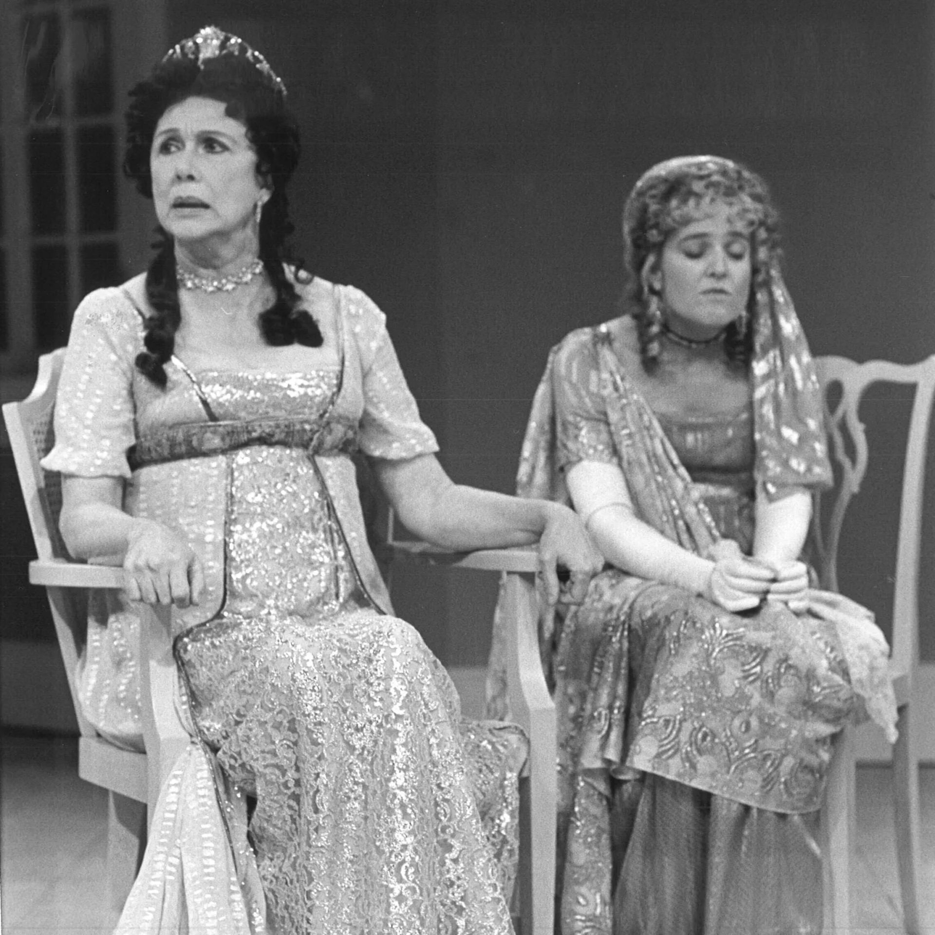 Two women are sitting together and are wearing gowns.