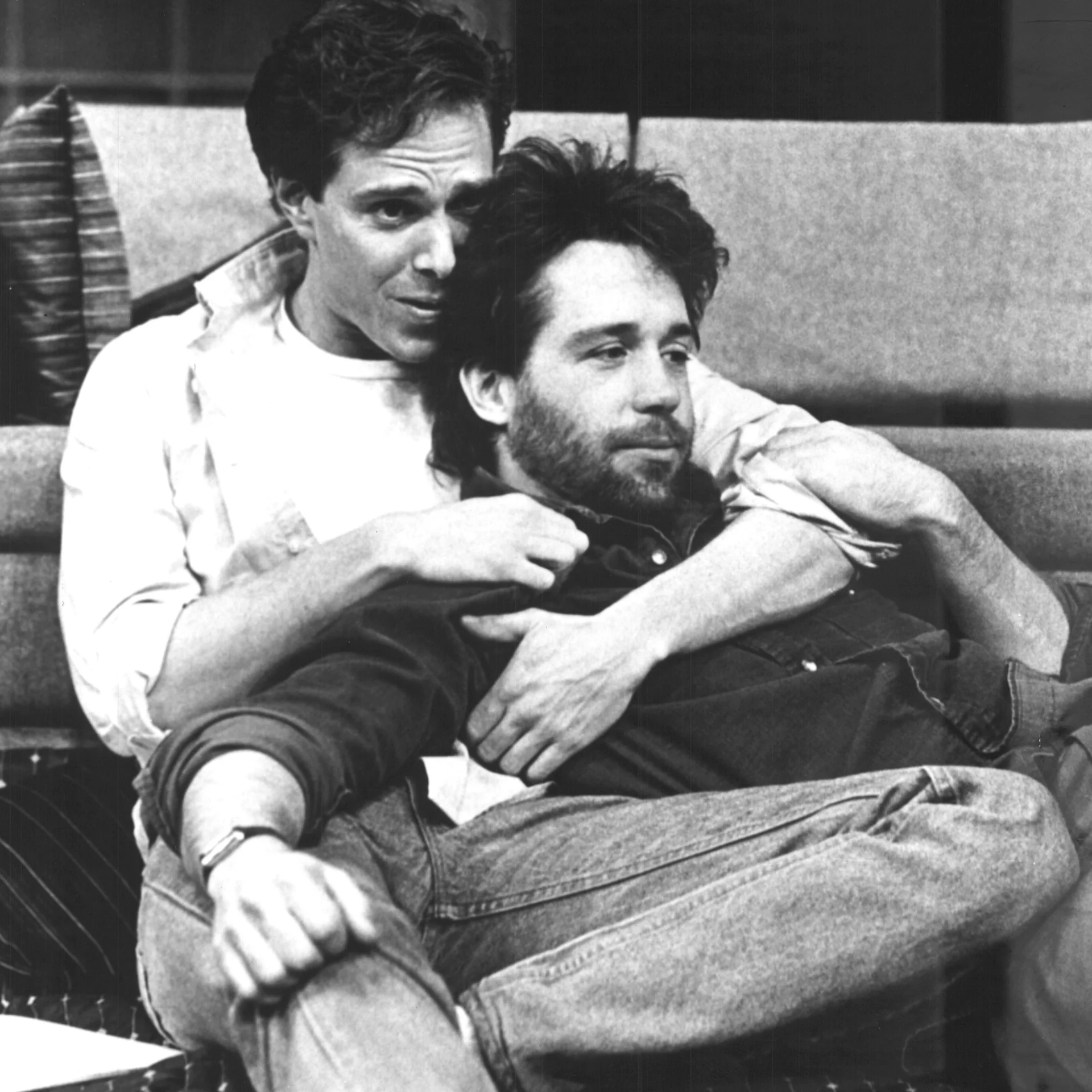 Two men are laying together cuddling.