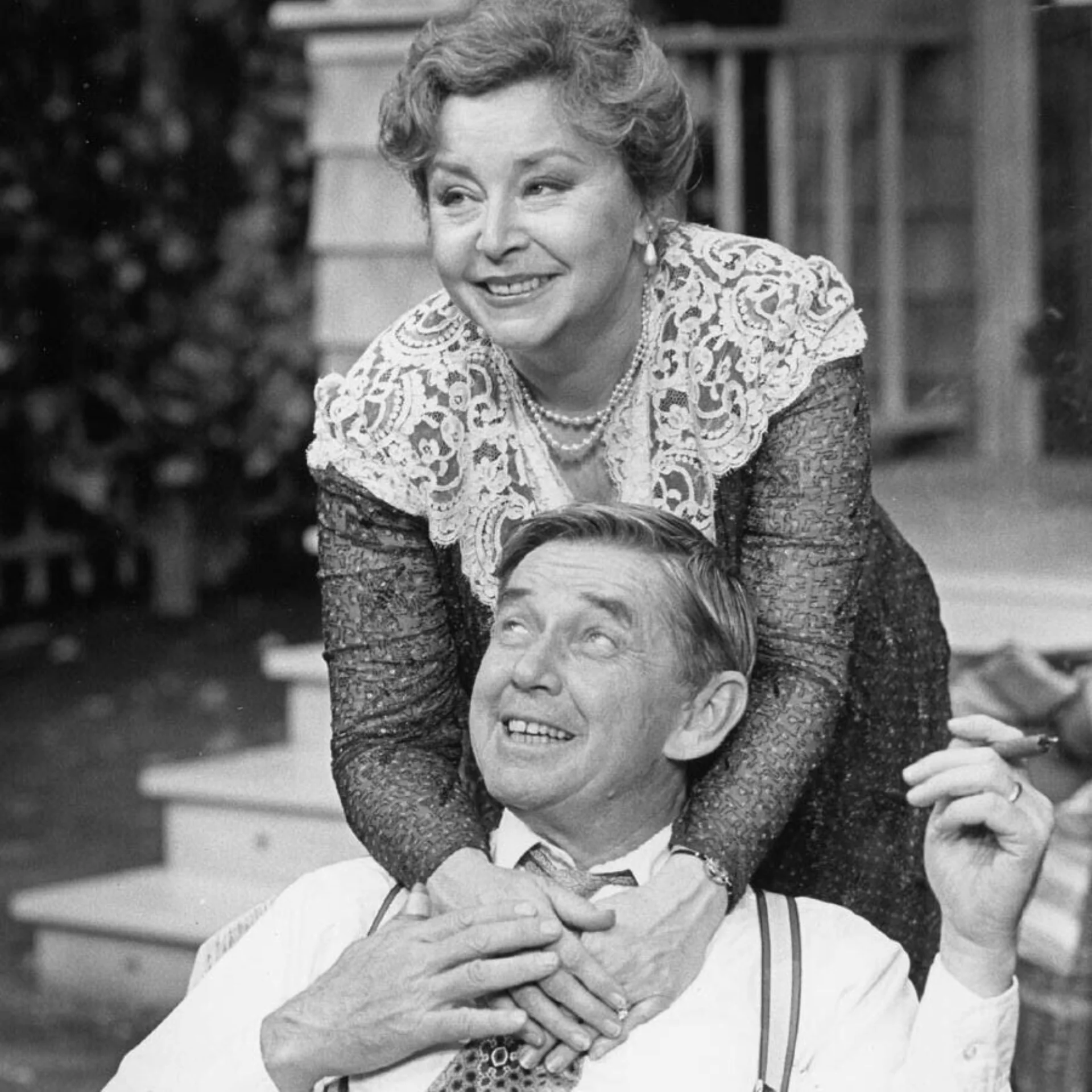 A woman is hugging a man from behind and their both smiling.