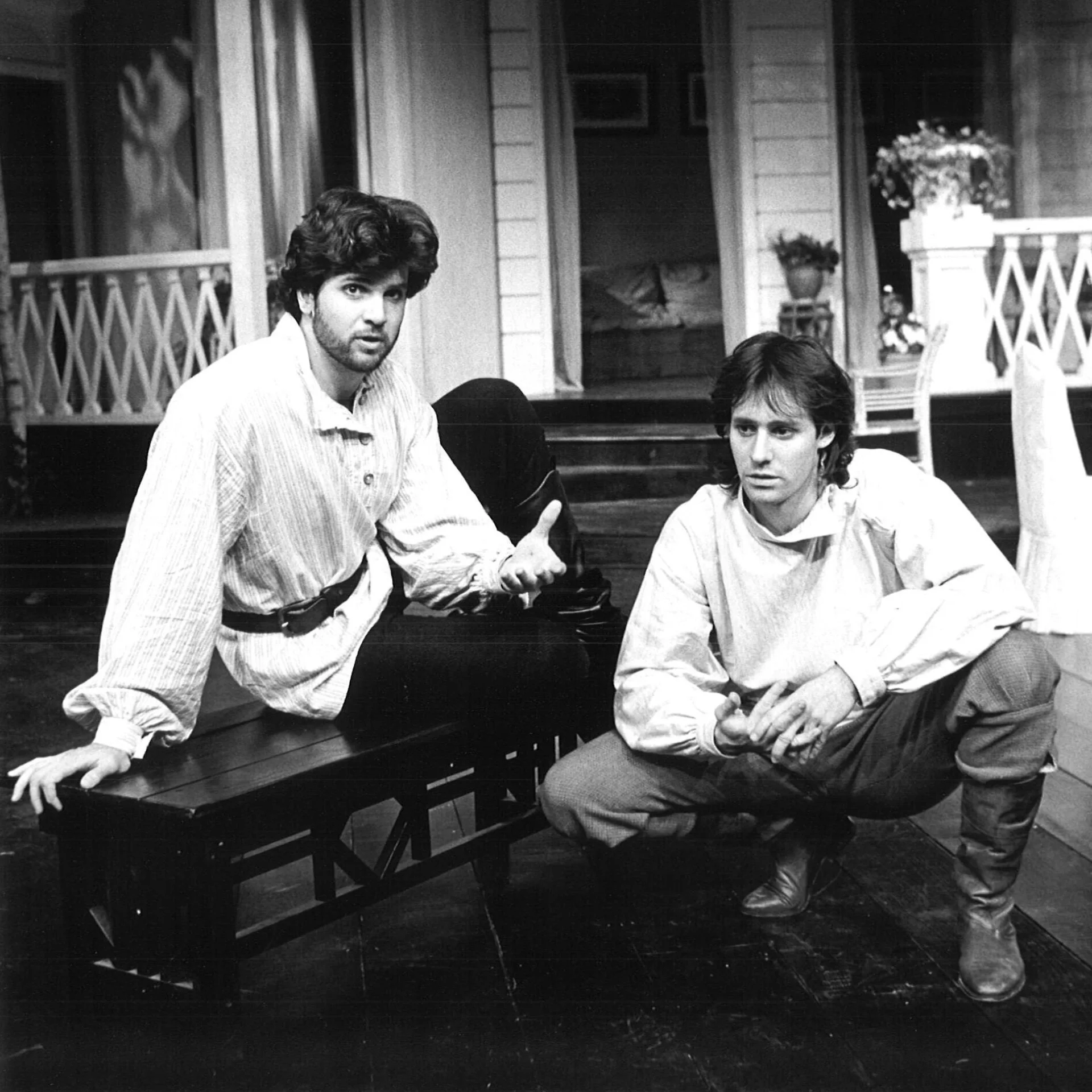 A man is sitting on a bench while another man is squatting next to him.