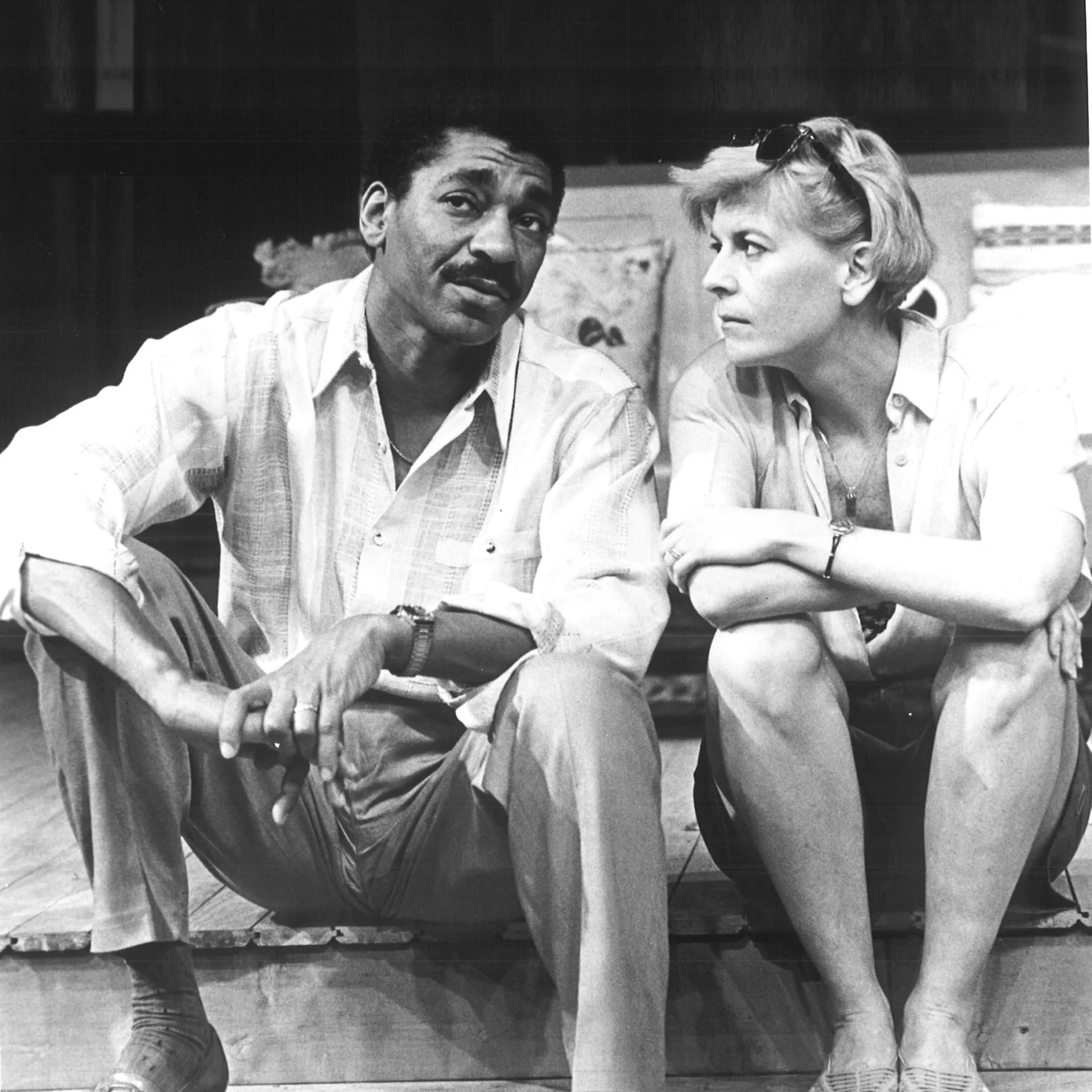 A man and woman are sitting on a porch together having a conversation.
