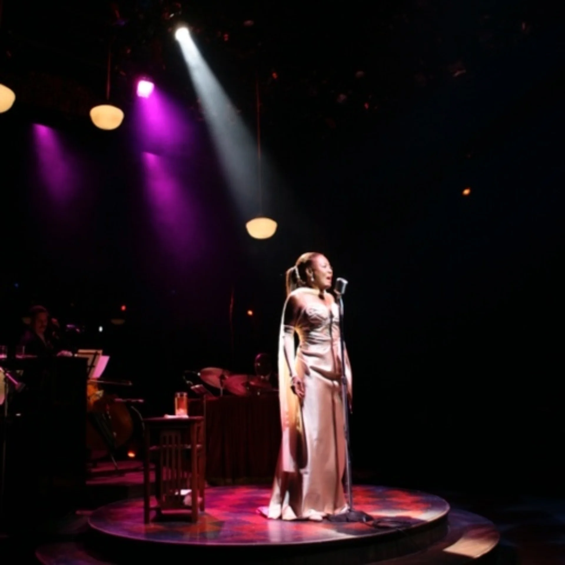 A spotlit woman singing into a microphone