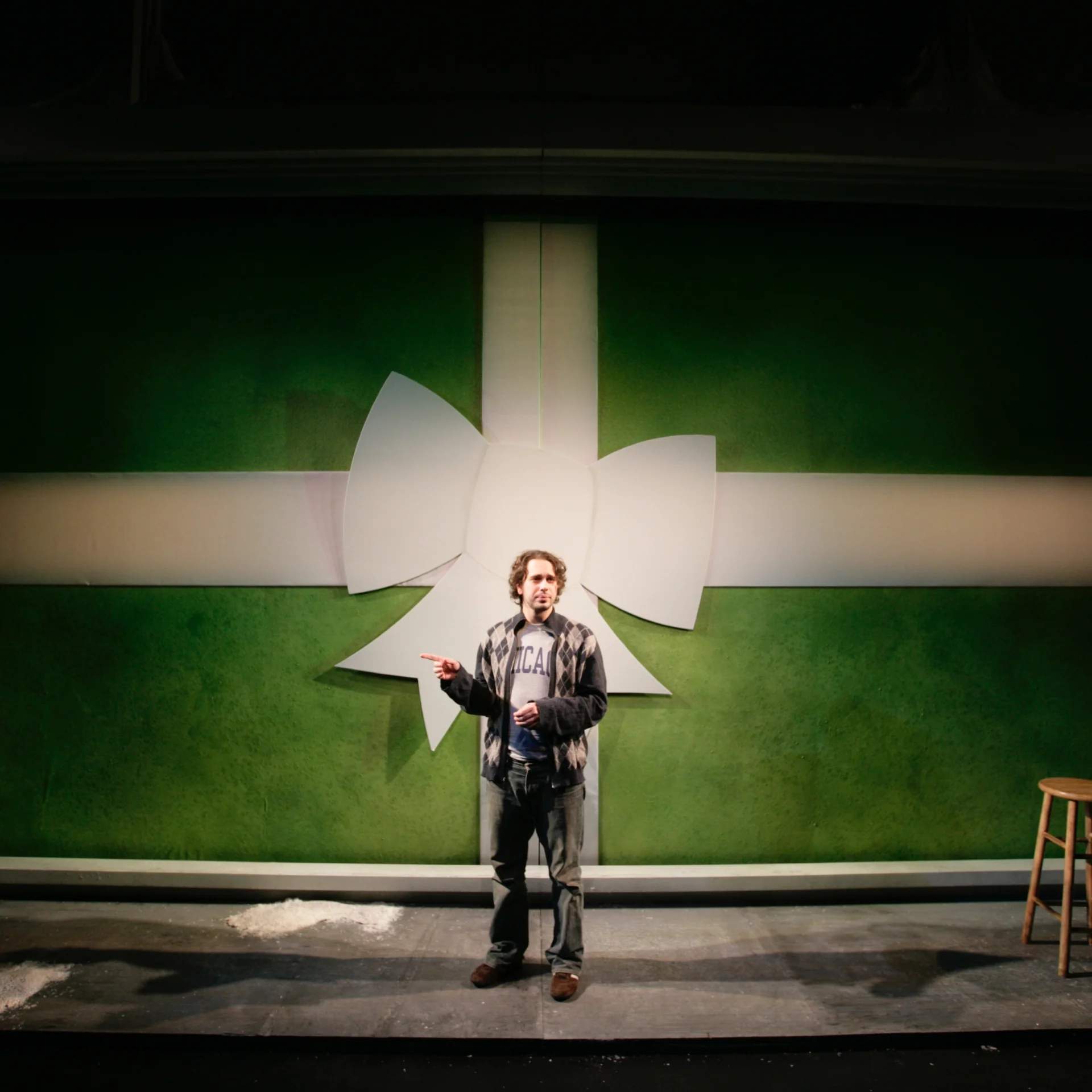 A man stands in front of green backdrop with a big bow