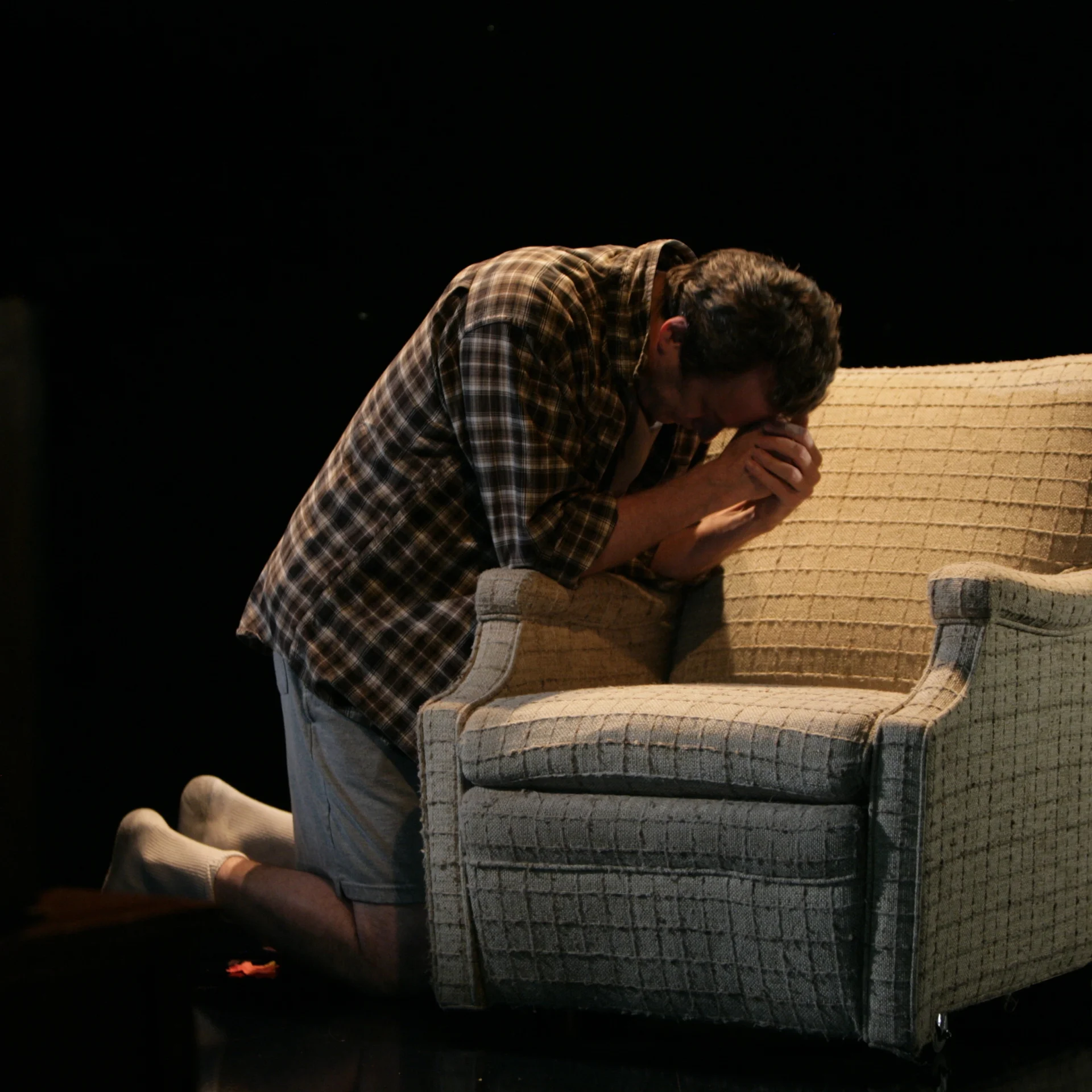 A man knees next to an armchair
