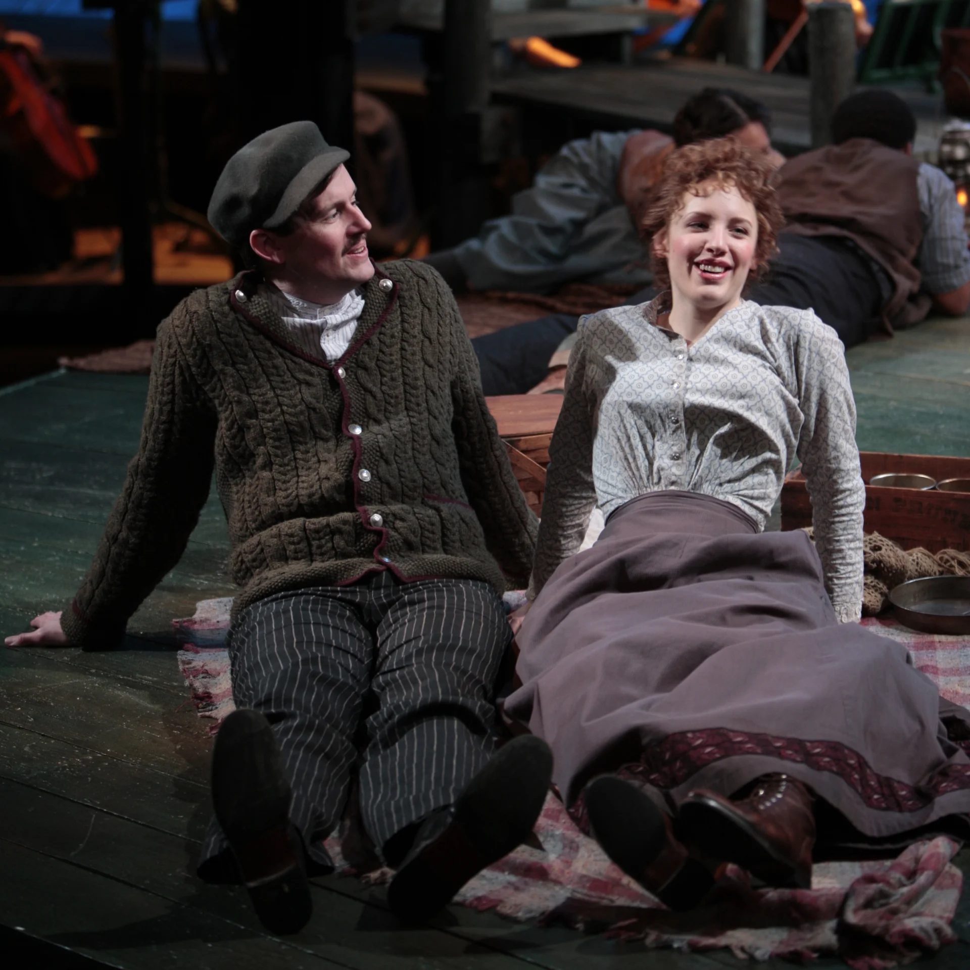 A man and woman sit side-by-side on a blanket