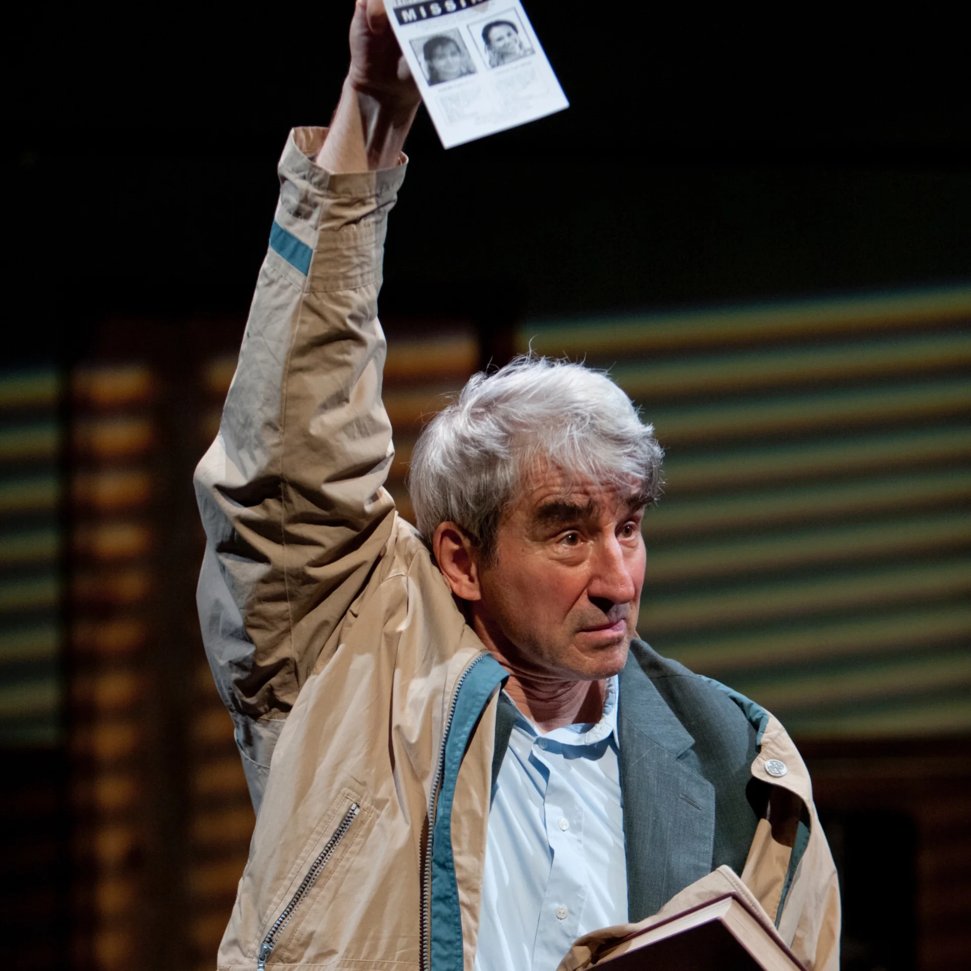 A older man holds up a "Missing" flying