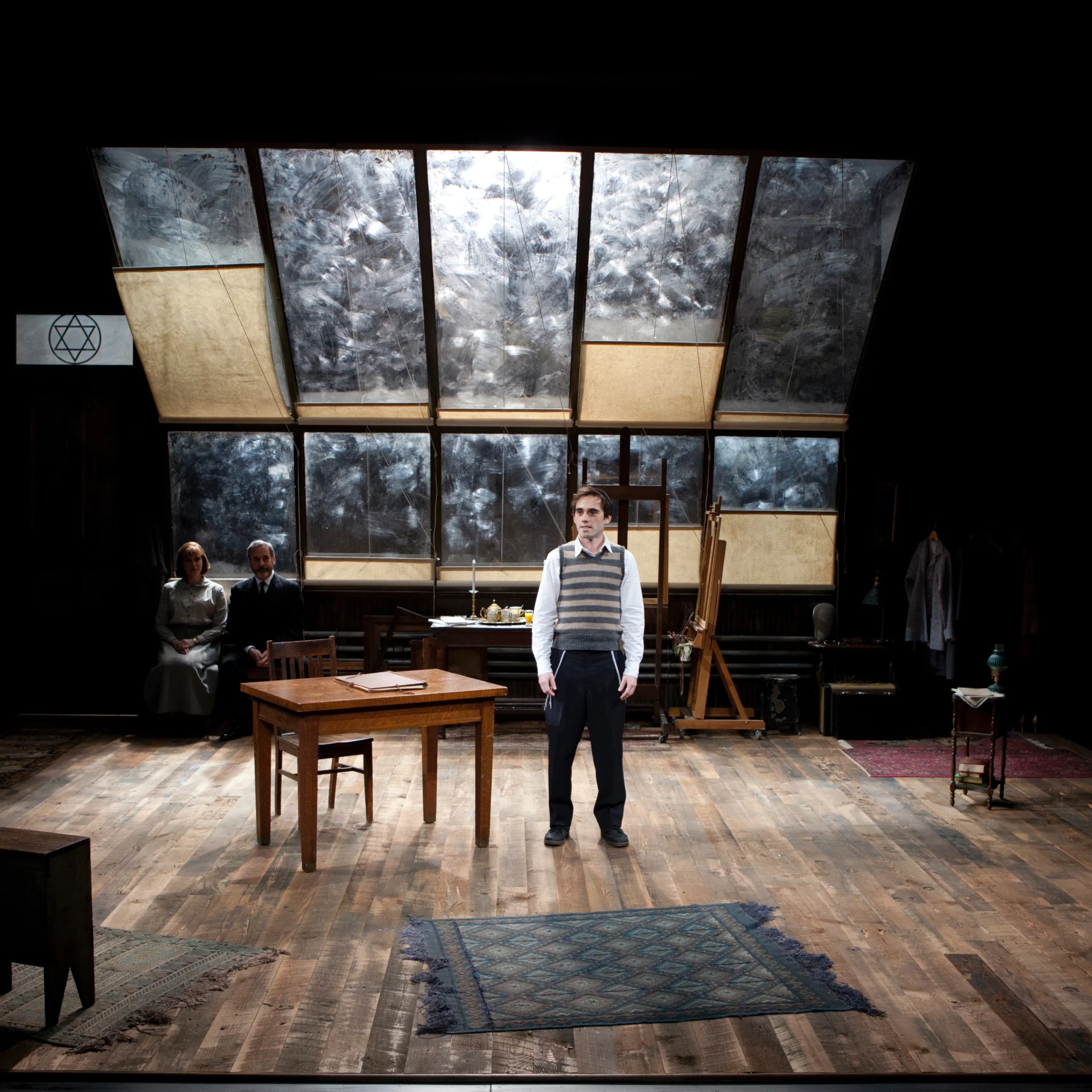 A man in a sweater vest stands beneath tilted glass ceiling panes