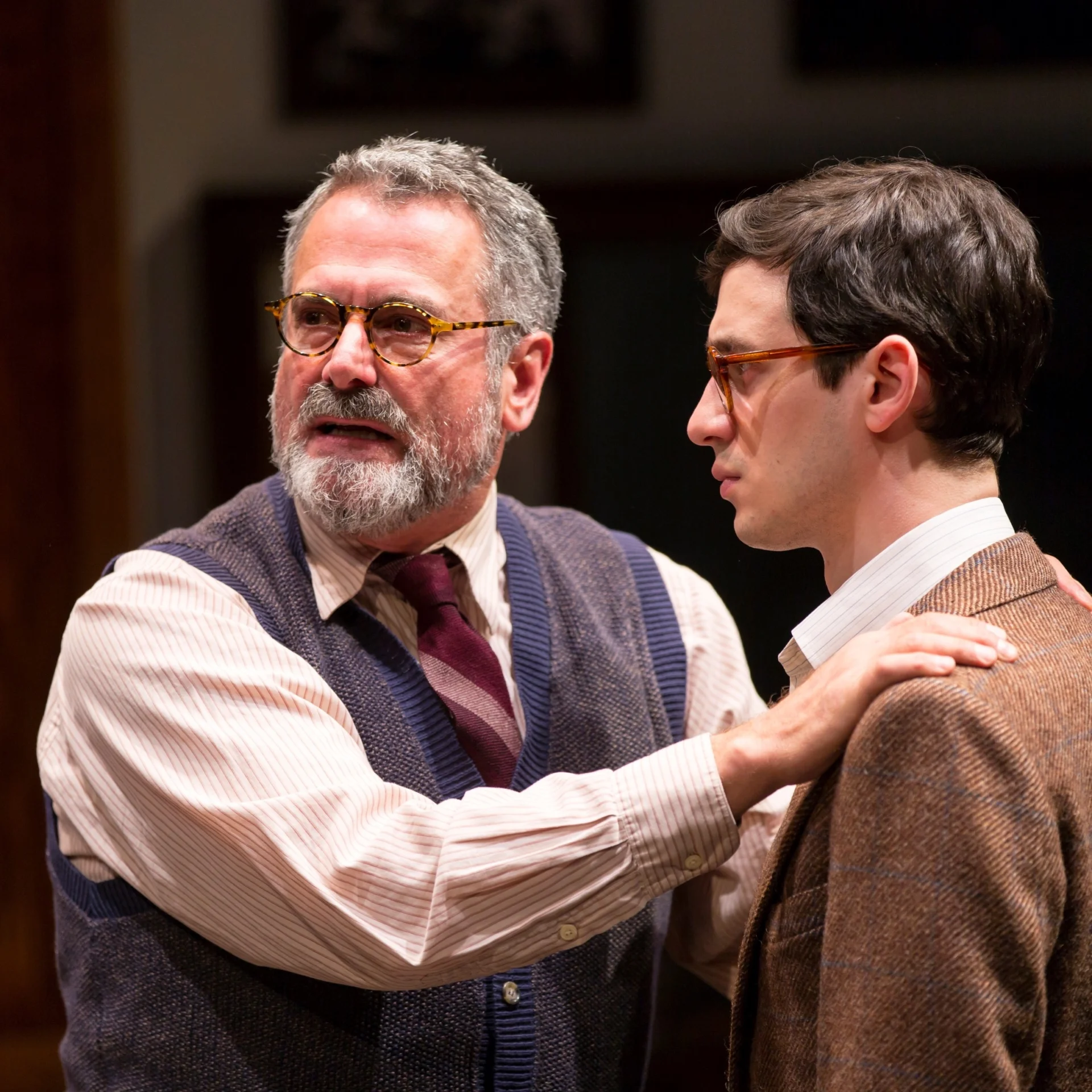 An older man puts his hands on a younger man's shoulders