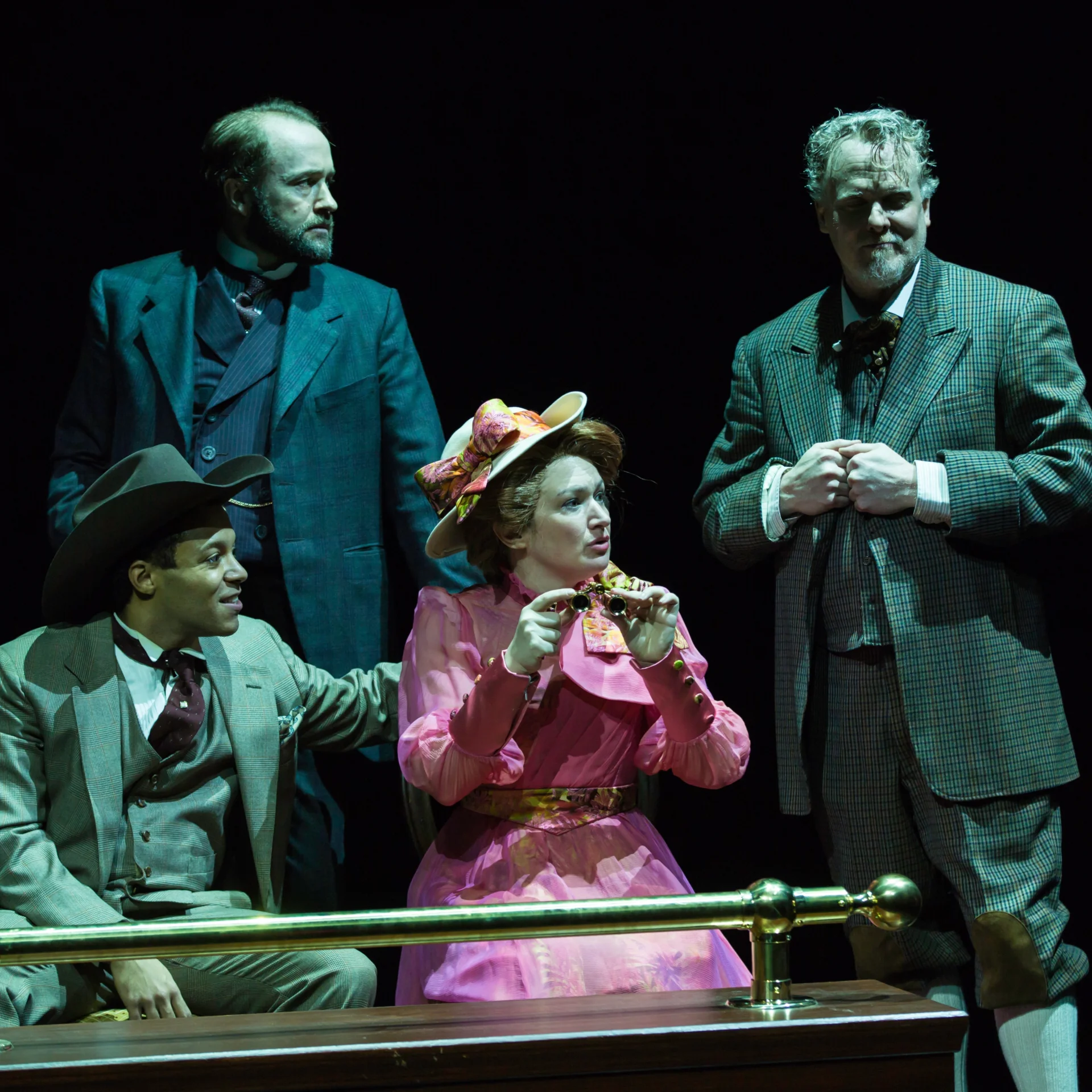 Four people behind a railing are awash in green light