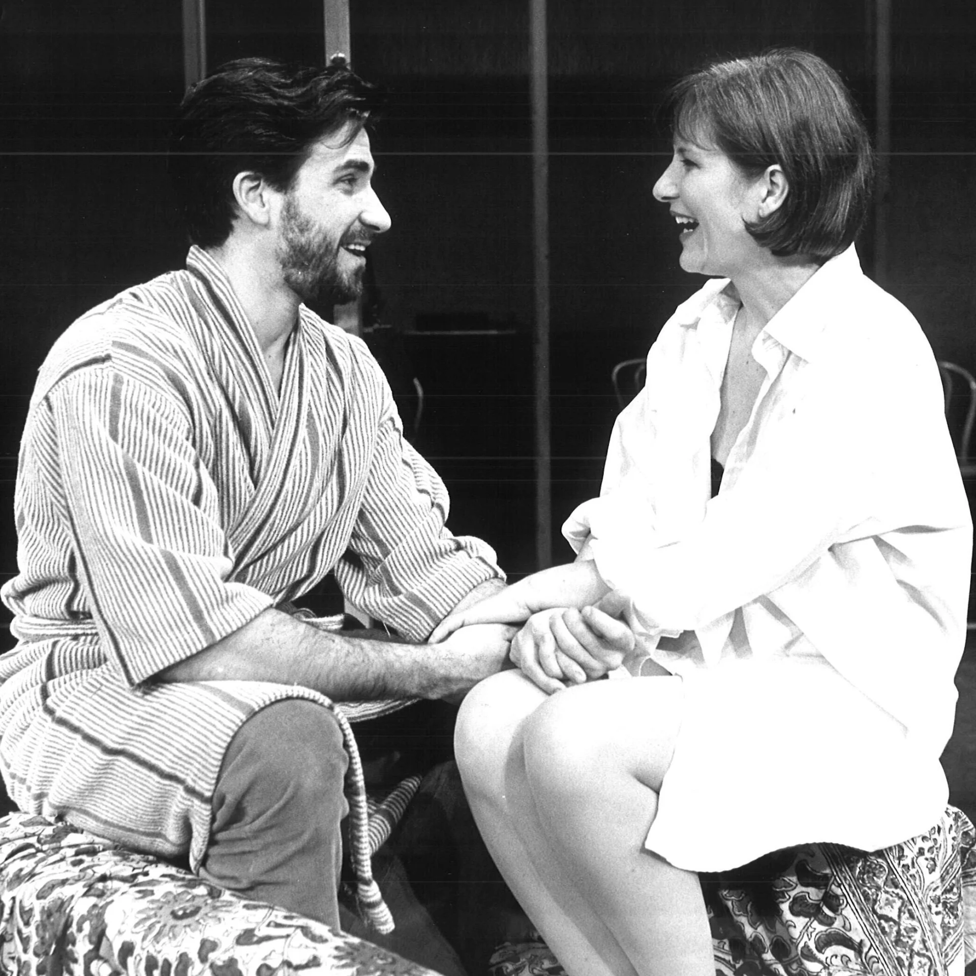 A man and woman are sitting on a coach holding hands.