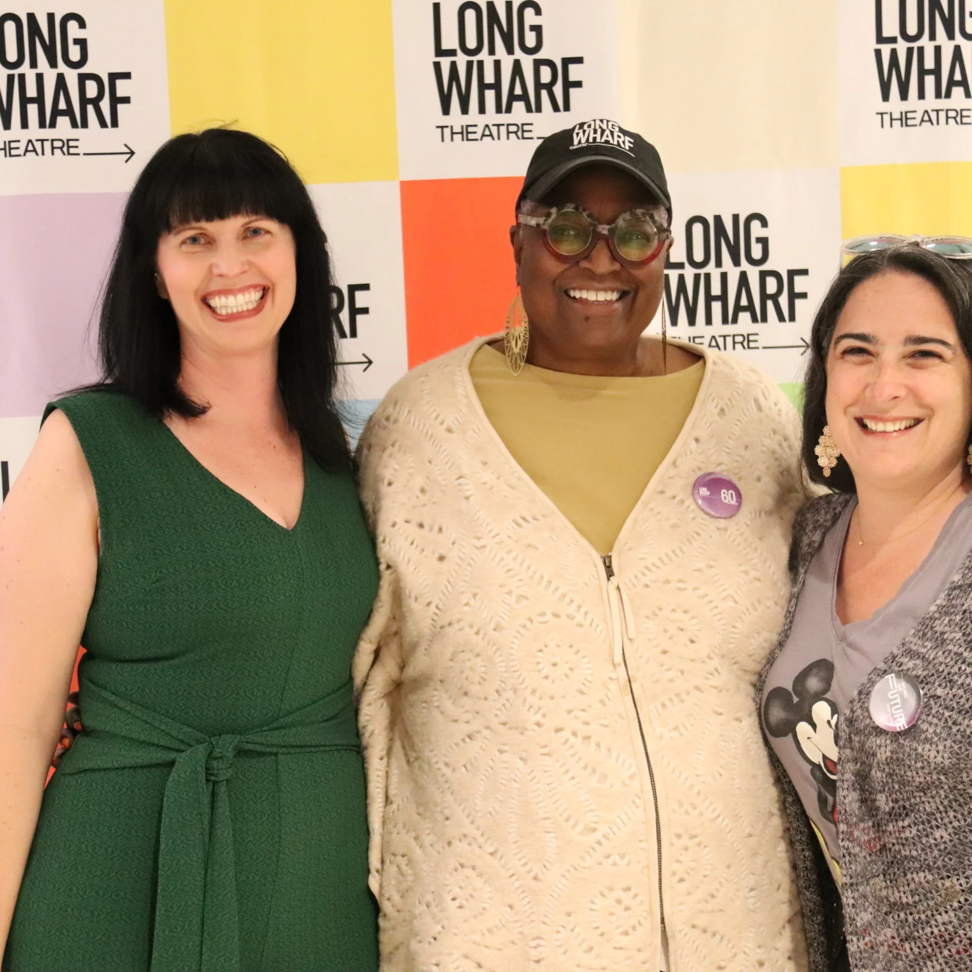 Three people smile for a photograph in front of a Long Wharf Theatre branded backdrop.